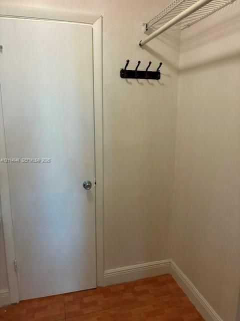 Storage area featuring a wood-finish floor, a wall-mounted four-hook rack, and an overhead wire shelving unit