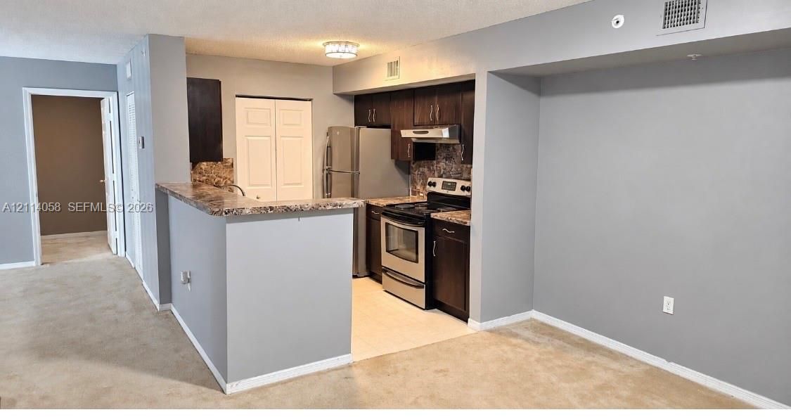 Kitchen featuring dark cabinetry, stainless steel appliances, laminate countertops, a breakfast bar, and tile flooring