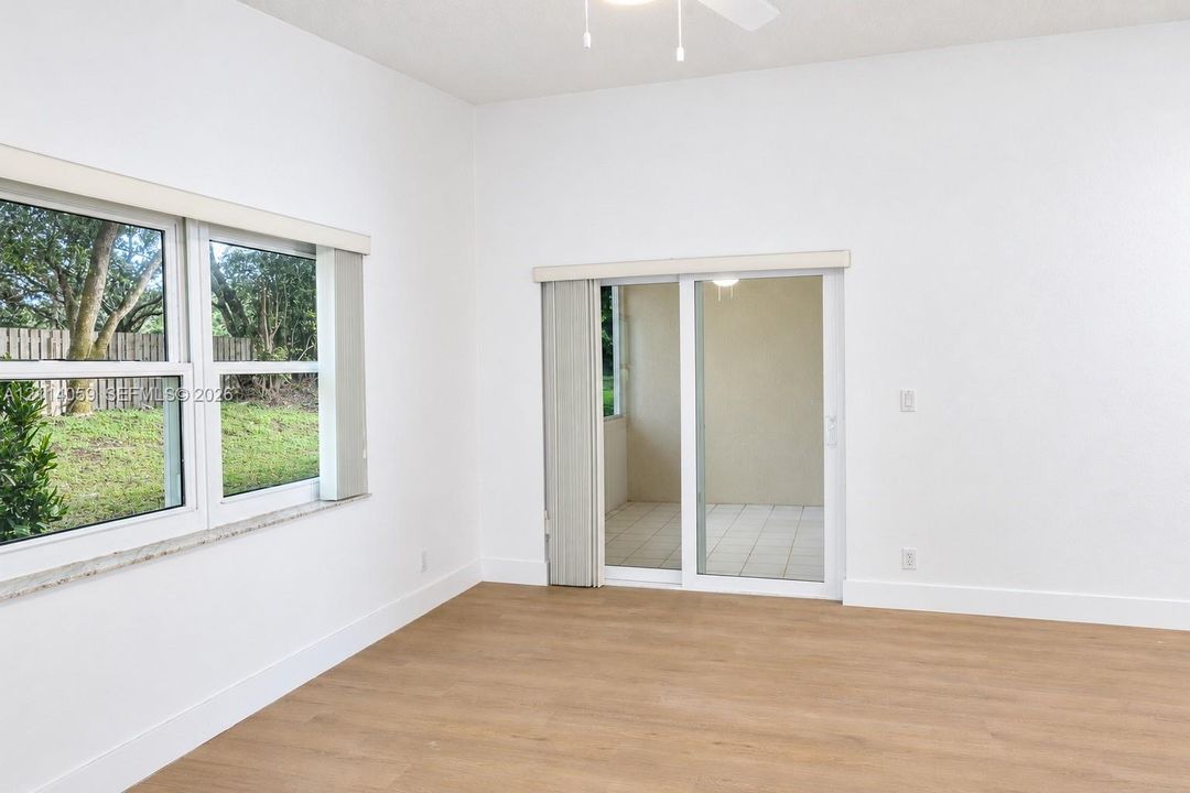 Interior space featuring wood-finish flooring, vaulted ceilings, dual-pane windows, and sliding glass doors opening to a tiled patio