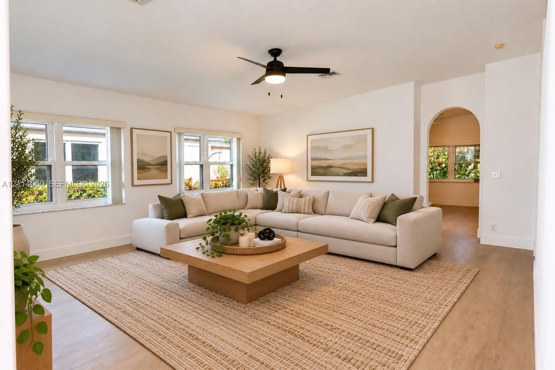 Spacious living area featuring wood-finish flooring, recessed lighting, a modern ceiling fan, and an architectural arched entryway