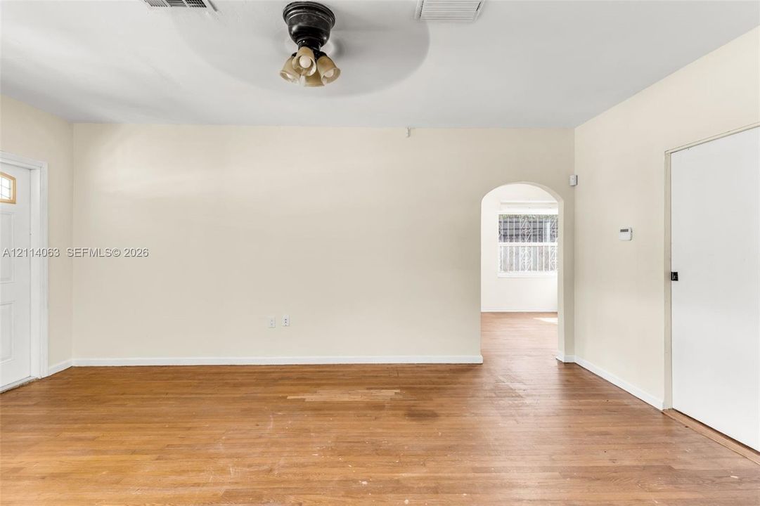 Interior space featuring wood-finish flooring, a neutral wall palette, a ceiling-mounted light fixture, and a rounded architectural archway