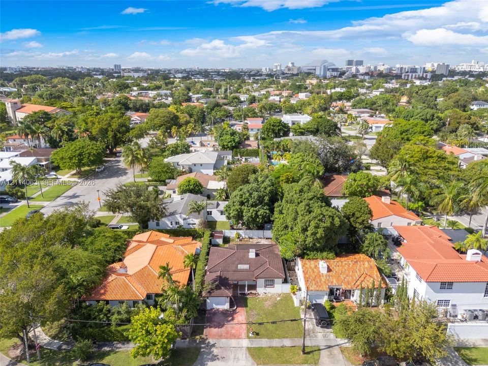 Aerial perspective featuring established residential streets with mature canopy trees, terra-cotta tile roof structures, and paved driveways
