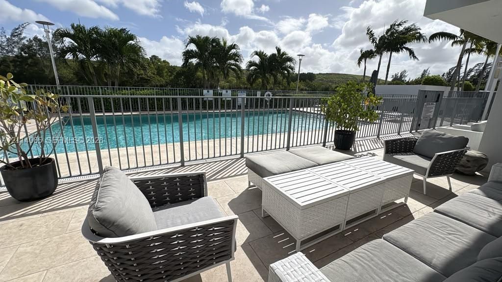 Outdoor terrace featuring stone-finish tiling, metal safety fencing, and a swimming pool
