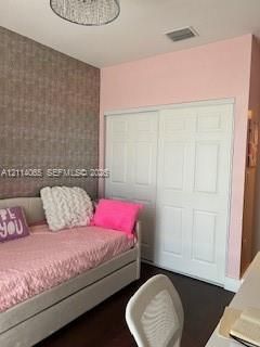 Textured accent wall, wood-finish flooring, sliding six-panel closet doors, and flush-mount ceiling light fixture