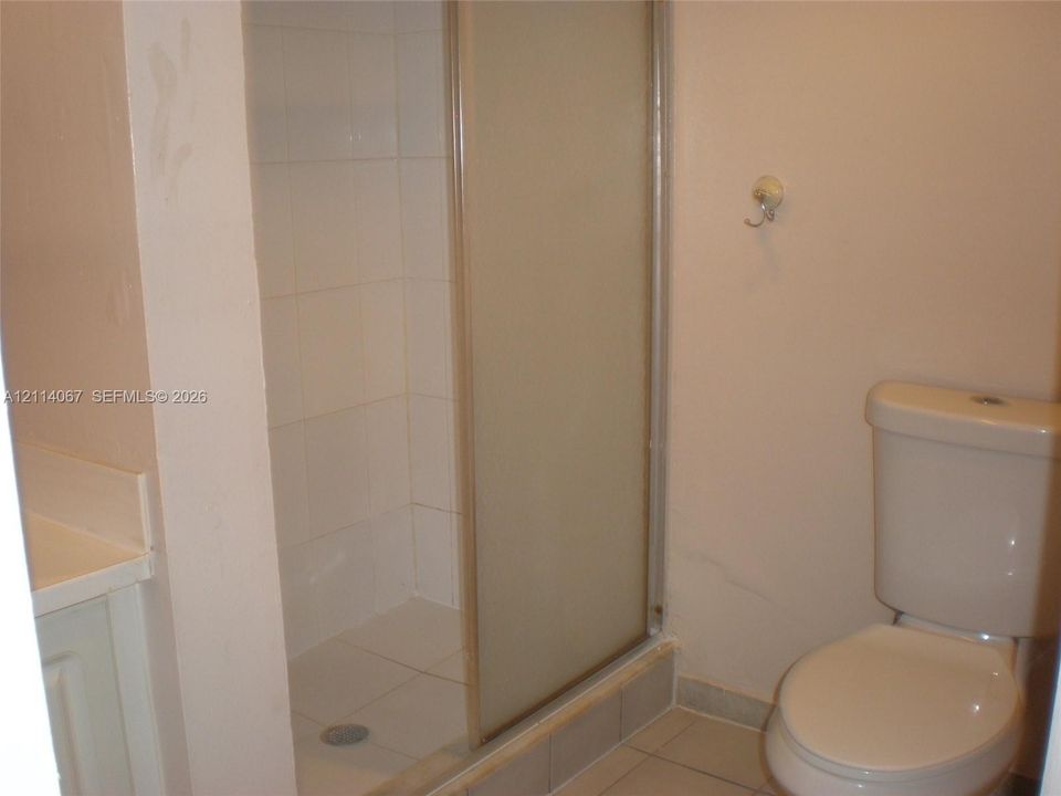 Bathroom featuring a shower stall with a framed sliding glass door and tile surround, a built-in vanity, and a porcelain toilet