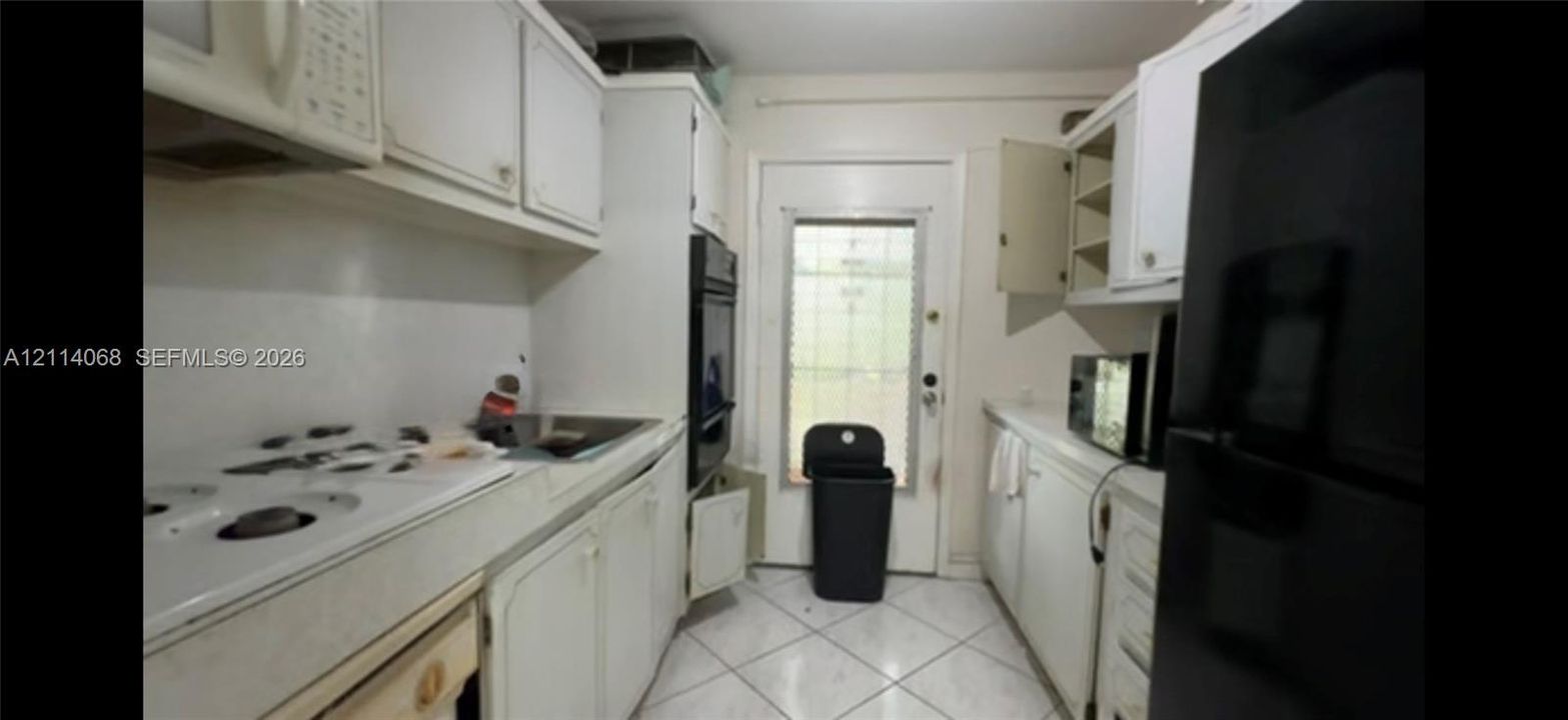 Kitchen featuring white cabinetry, built-in wall oven, flat-surface cooktop, and tile flooring