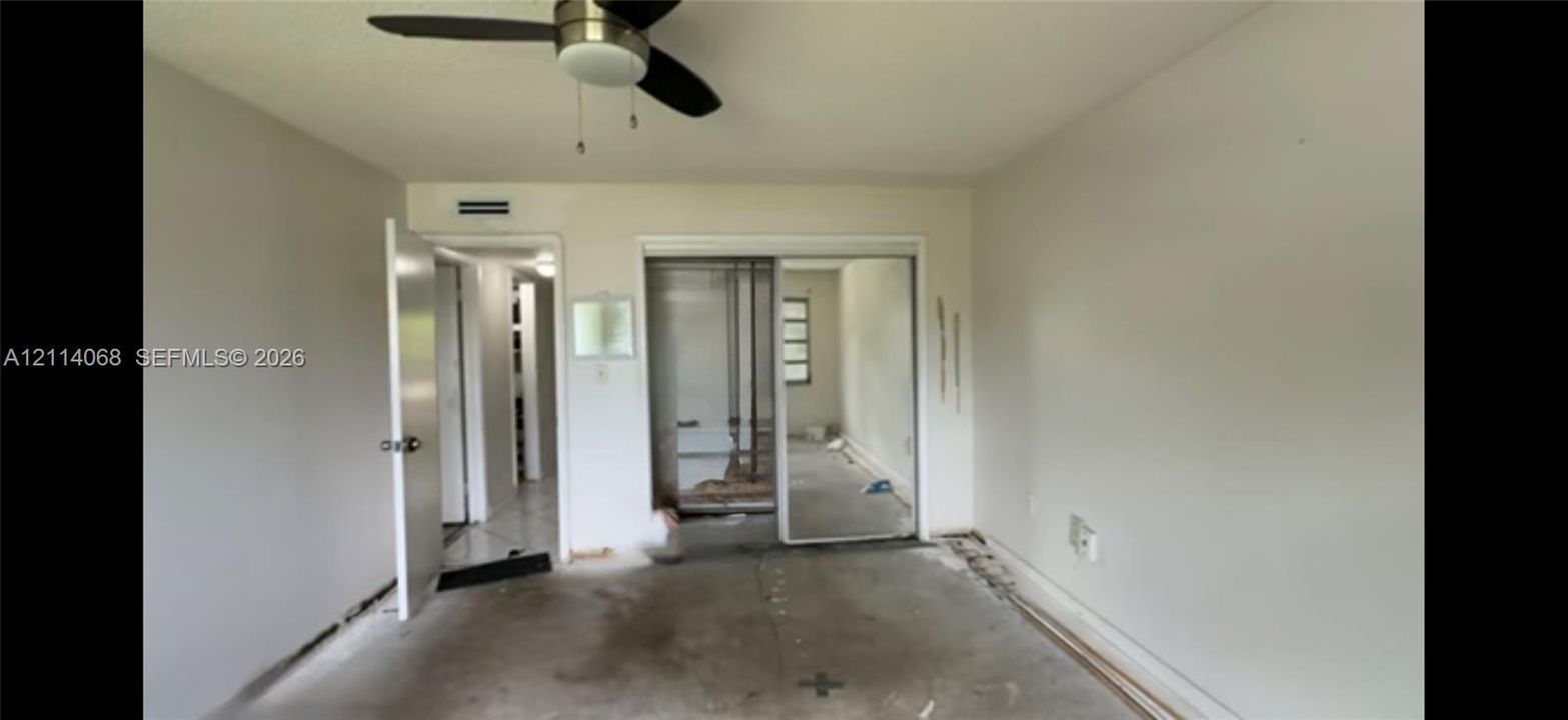 Room featuring a ceiling fan with integrated lighting and sliding mirrored closet doors