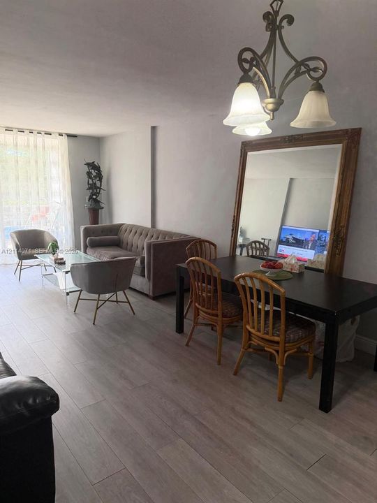 Wood-finish flooring, multi-light hanging chandelier, and floor-to-ceiling drapery