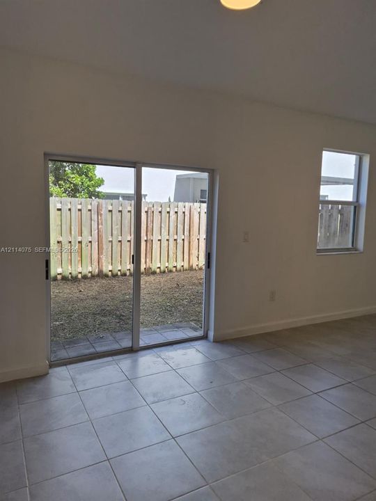 Neutral-toned ceramic tile flooring, sliding glass door, single-hung window, and fenced outdoor space