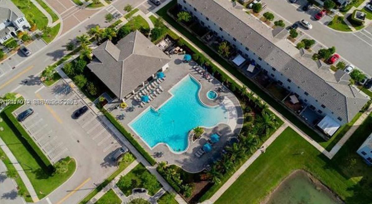 Community clubhouse featuring a swimming pool, integrated spa, paved pool deck, and landscaped surroundings
