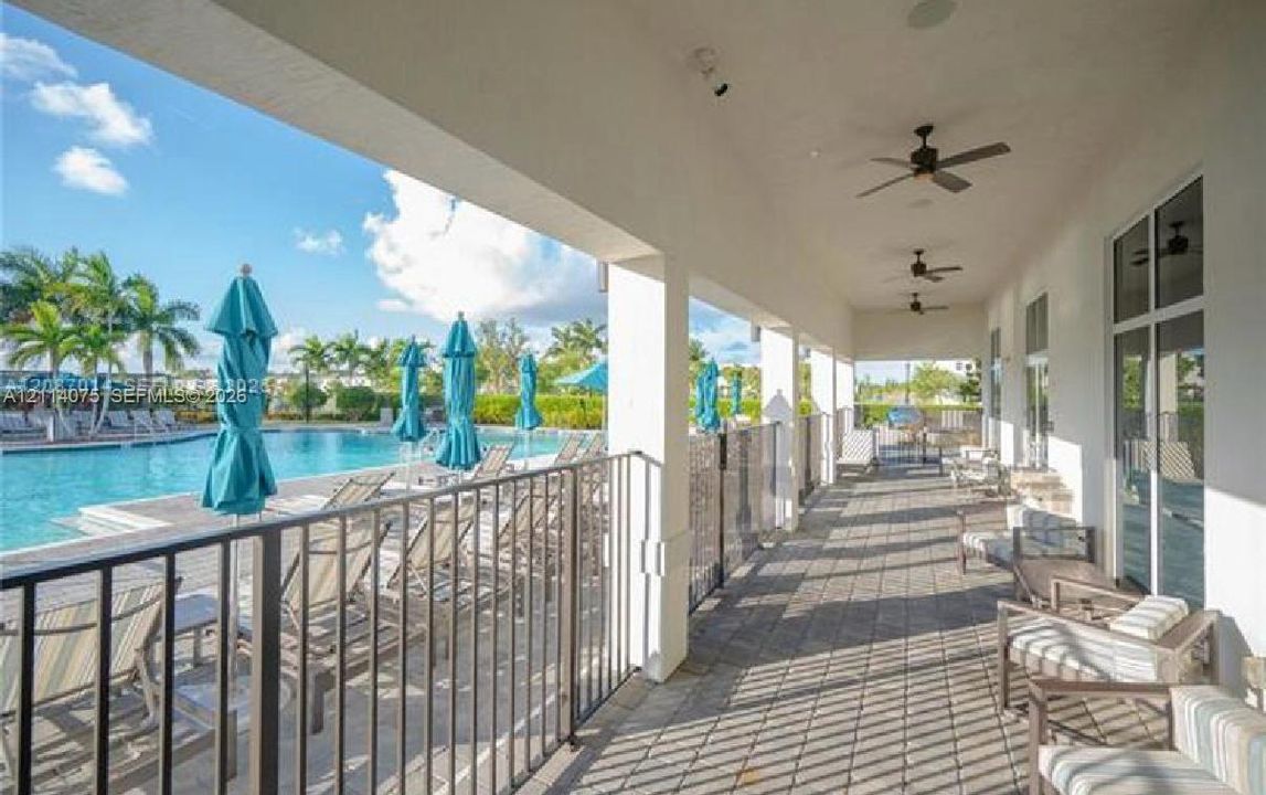Covered outdoor patio featuring stone-paver flooring, ceiling fans, recessed lighting, and a metal perimeter railing