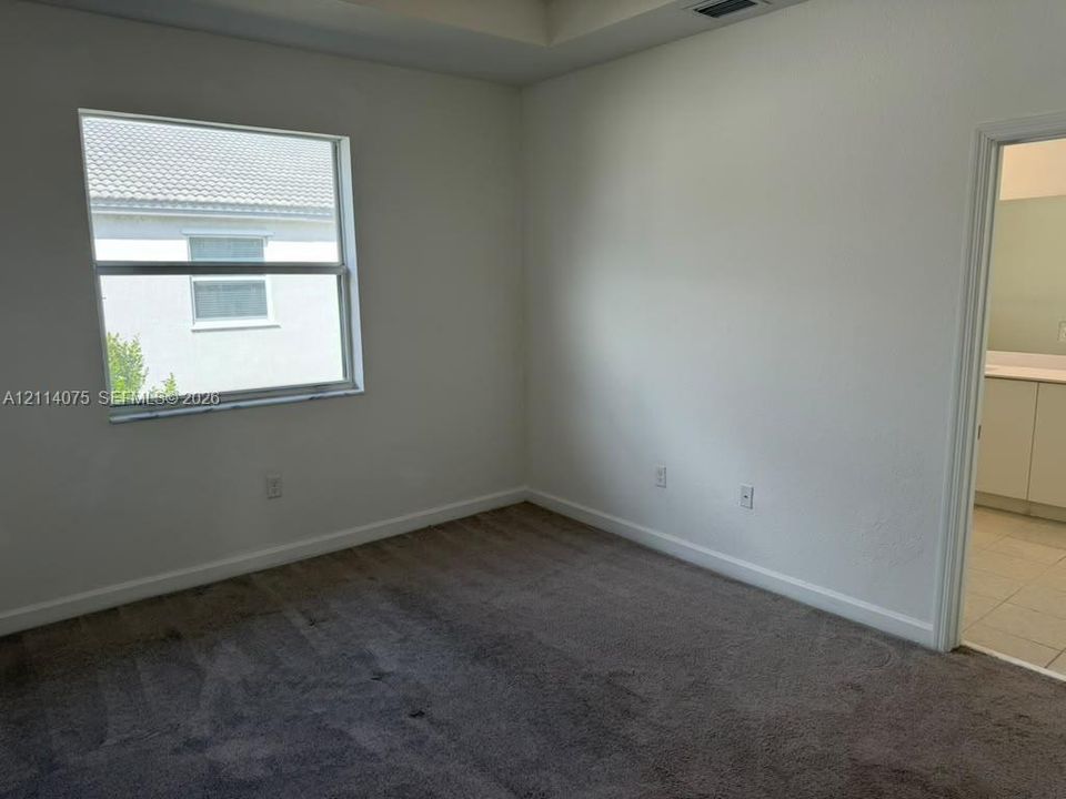 Interior space featuring neutral-toned carpeting, a tray ceiling, and a single-pane window
