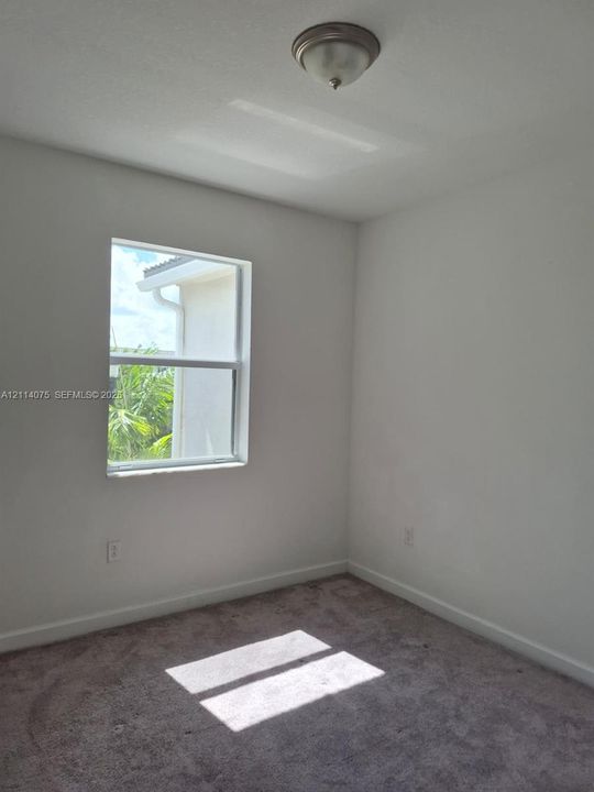 Neutral-toned interior room featuring wall-to-wall carpeting, a single-hung window, and a flush-mount ceiling light fixture