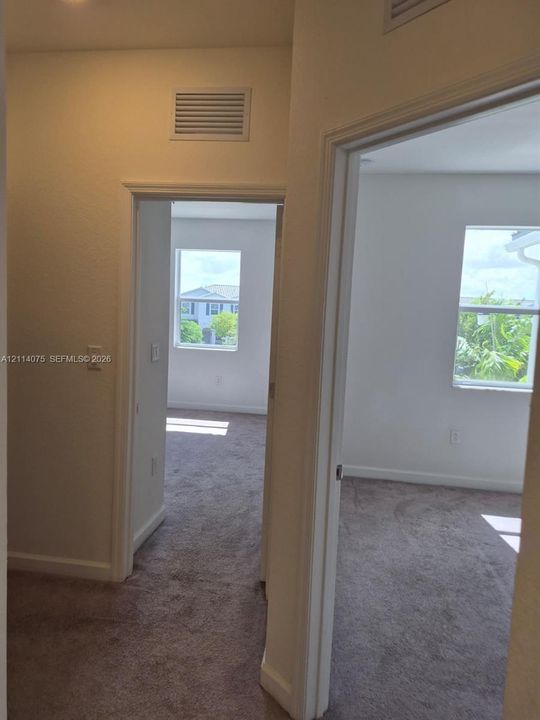 Neutral-toned carpeted flooring, white interior walls, and multiple single-hung windows providing natural light