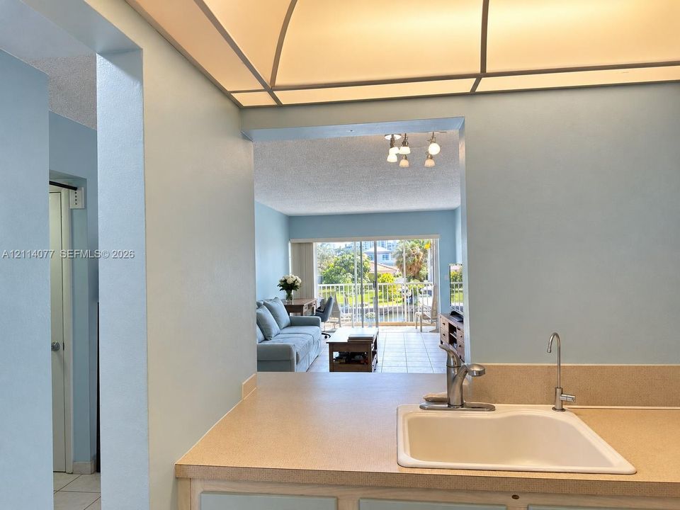 Kitchen featuring solid-surface countertops, integrated sink, and gooseneck faucet beneath a recessed tray ceiling with integrated lighting