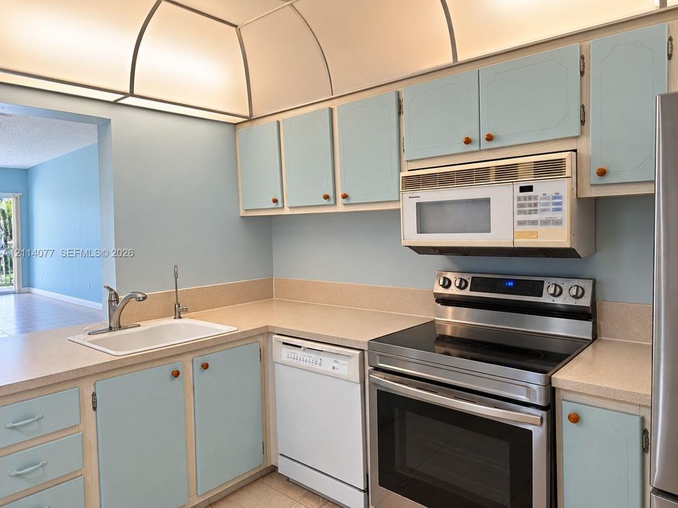 Kitchen featuring built-in cabinetry, solid-surface countertops, integrated cove lighting, and stainless steel appliances