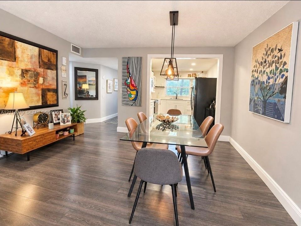 Dining area featuring wood-finish flooring, a geometric pendant light fixture, and neutral wall tones