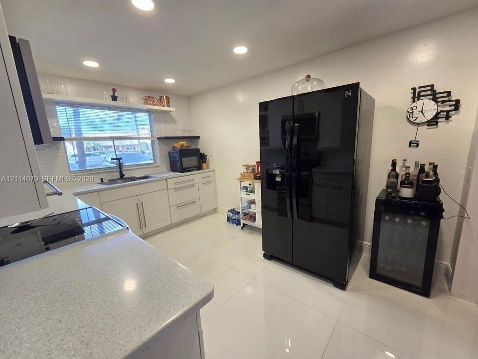 Kitchen featuring white cabinetry, solid surface countertops, recessed lighting, and tile flooring