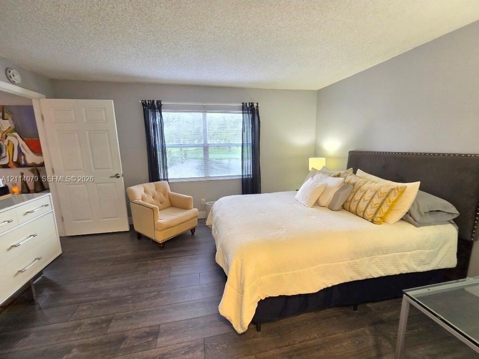 Room featuring wood-finish flooring, a large window, neutral wall paint, and a textured ceiling