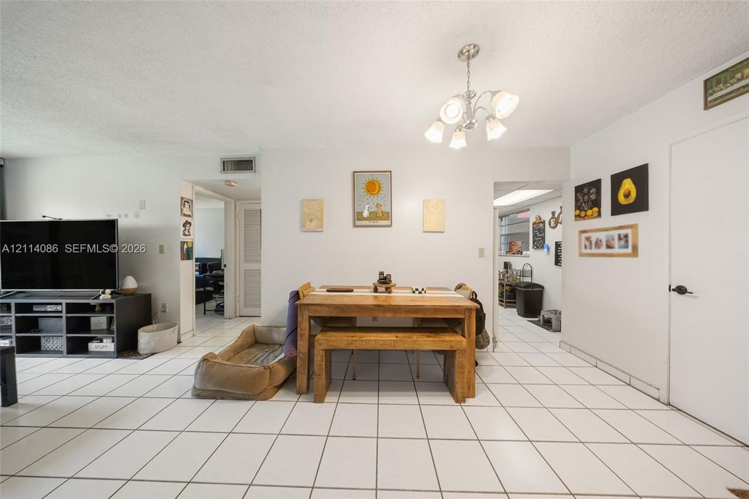 Open-concept area featuring white ceramic tile flooring and a multi-arm polished metal chandelier
