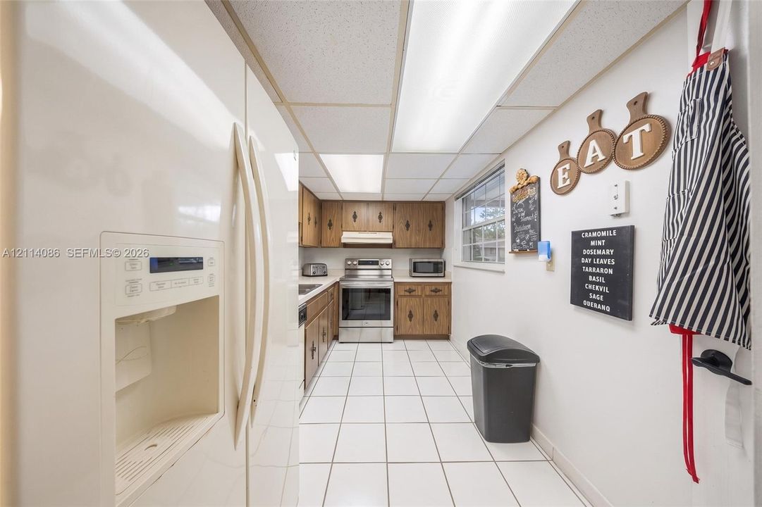 Kitchen featuring stainless steel appliances, stained wood cabinetry, ceramic tile flooring, and integrated lighting