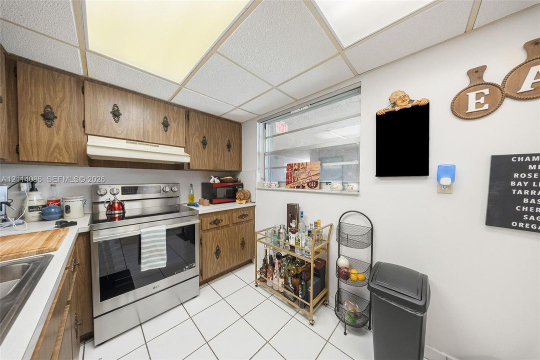 Kitchen featuring wood-finish cabinetry, stainless steel range, drop-in sink, and ceramic tile flooring