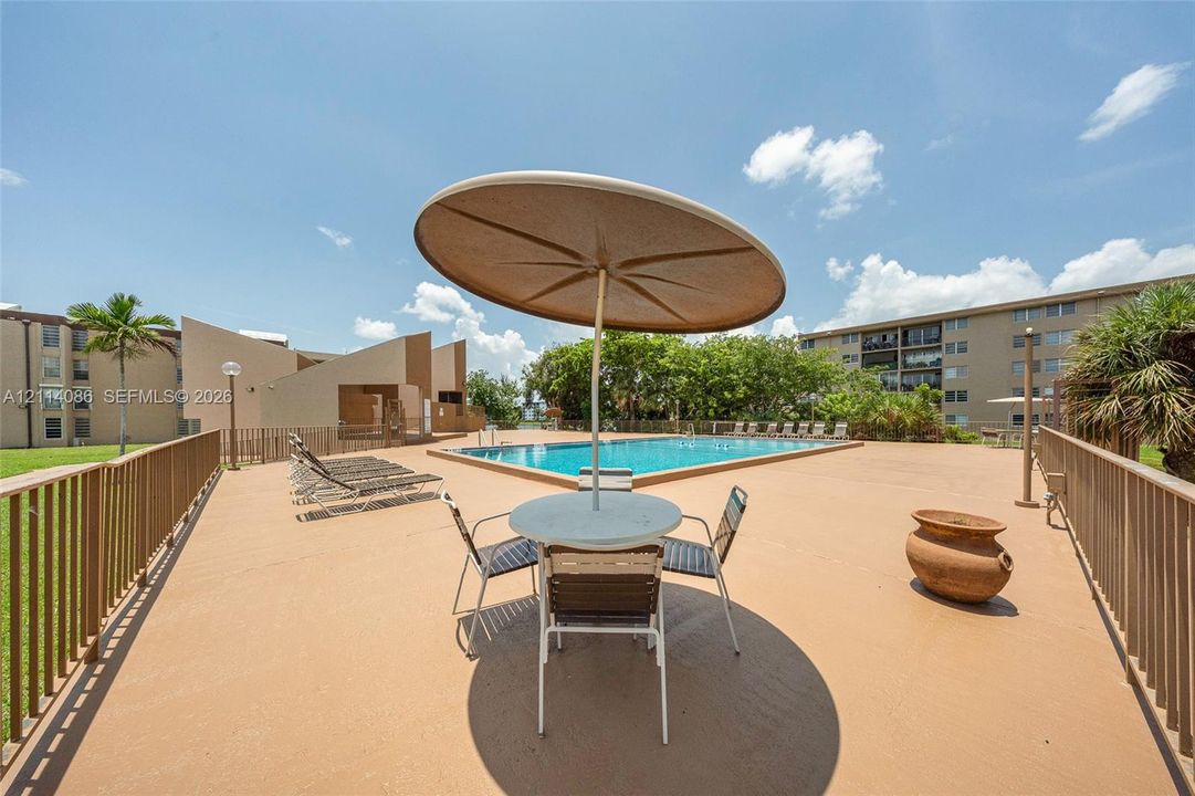 Swimming pool with expansive concrete pool deck and metal perimeter fencing