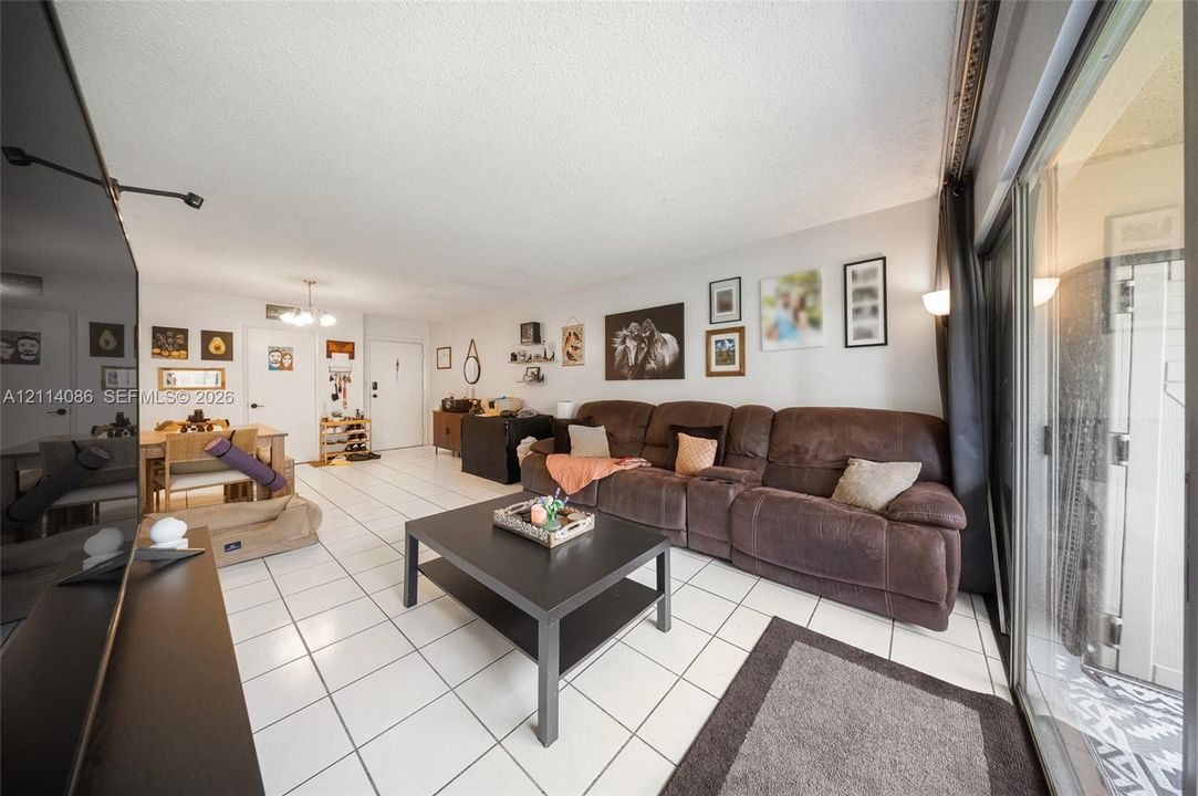 Open-concept living space featuring large-format ceramic tile flooring, sliding glass door, and recessed lighting