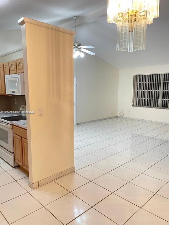 Vaulted ceilings, tile flooring, built-in cabinetry, ceiling fan, and multi-tiered glass chandelier