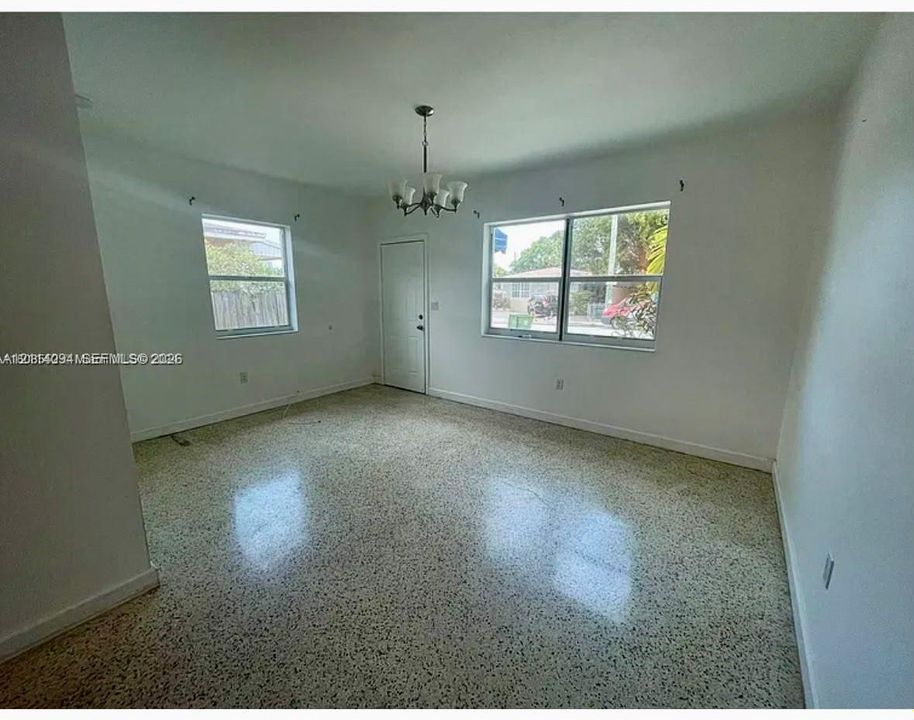 Interior space featuring terrazzo flooring, multi-pane windows, a central chandelier, and a solid-panel entry door