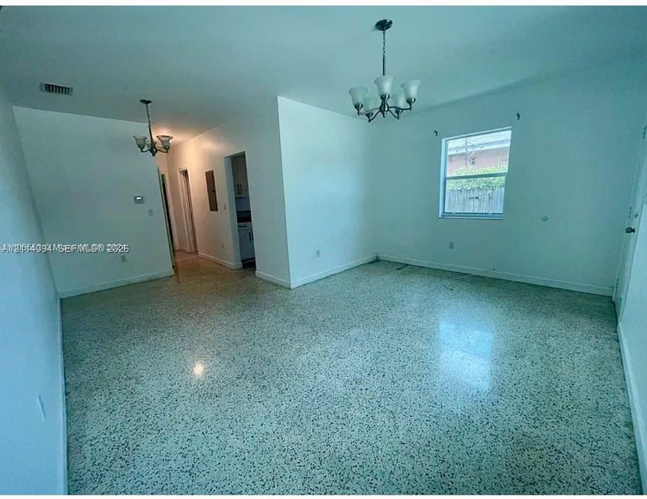Interior space featuring polished terrazzo flooring, two traditional five-light chandeliers, and neutral wall tones