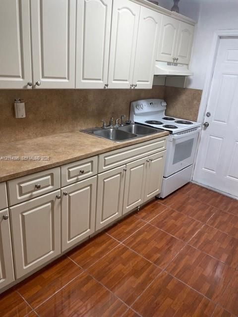 Kitchen featuring neutral-toned cabinetry, dual-basin stainless steel sink, tile-finish flooring, and a built-in range hood