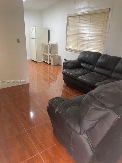 Glossy ceramic tile flooring featuring a wood-tone finish and horizontal window blinds