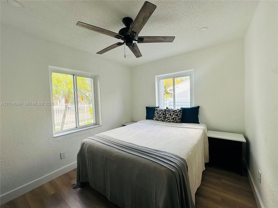 Room featuring wood-finish flooring, recessed lighting, dual windows, and a ceiling fan with dark wood-toned blades