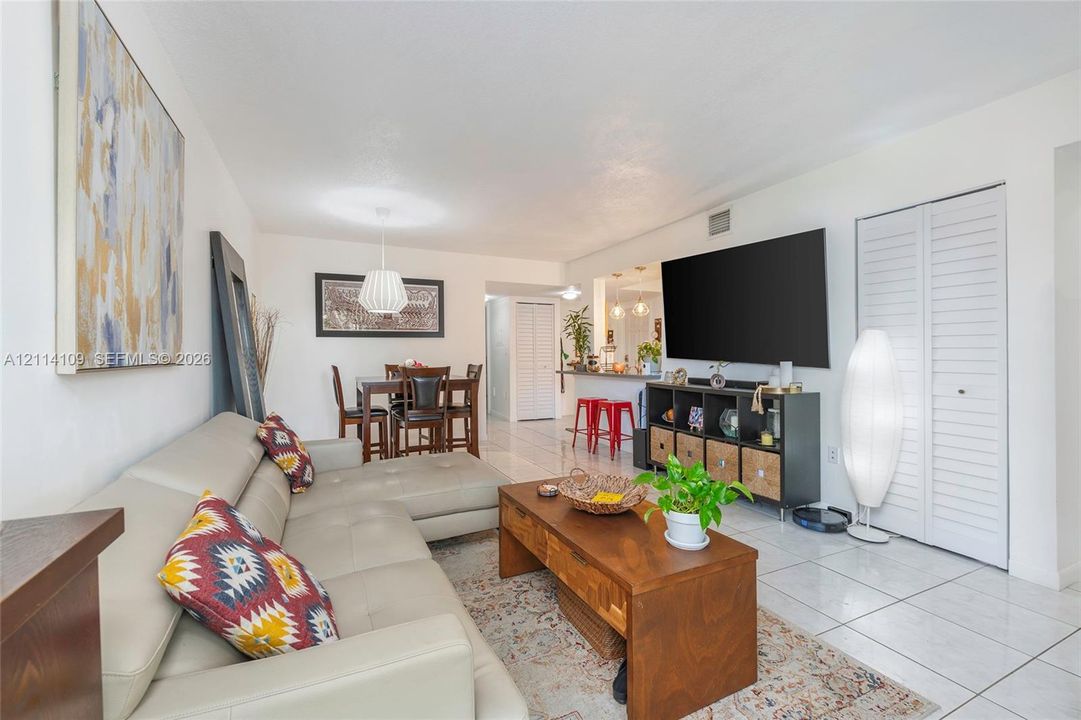 Open-concept interior featuring light-colored floor tiling, recessed lighting, white louvered closet doors, and a breakfast bar counter