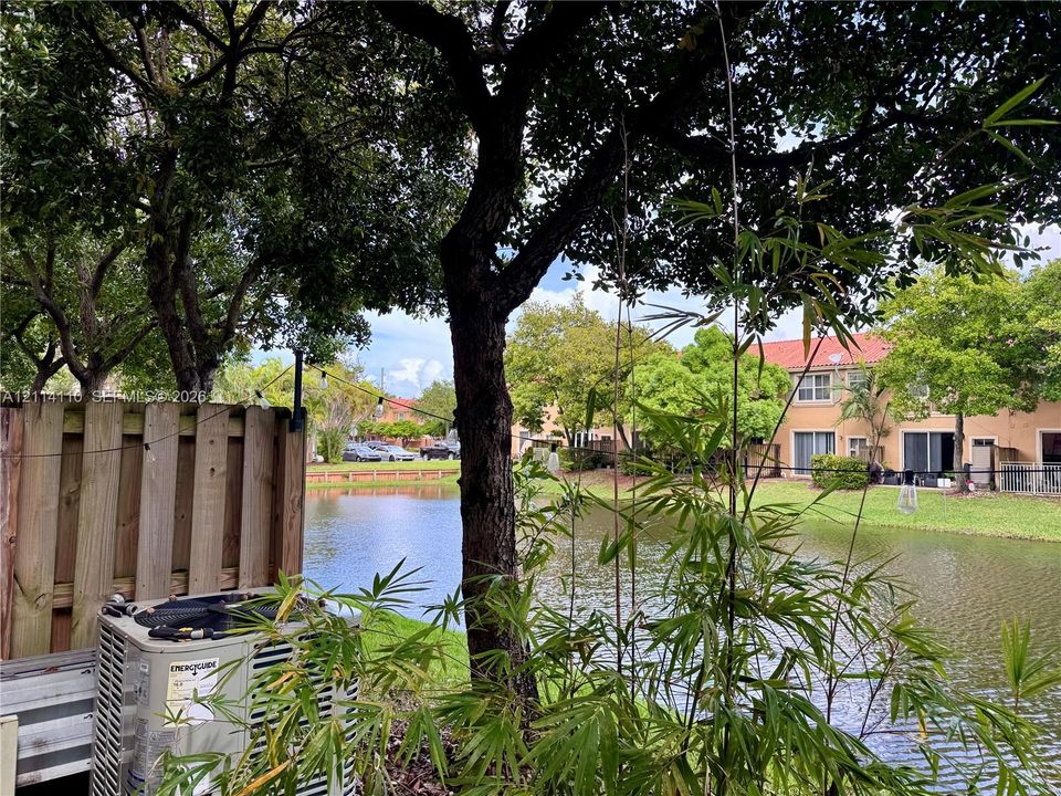 Waterfront lot featuring mature trees, a wood-slatted privacy fence, and native vegetation