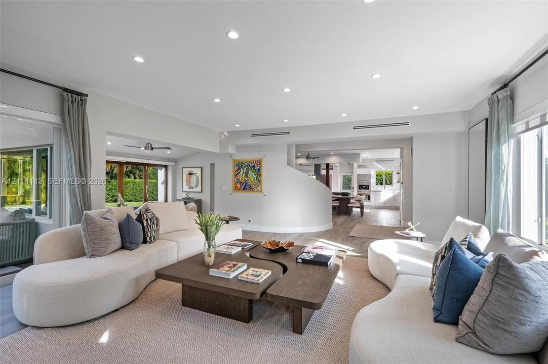 Open-concept interior featuring recessed lighting, a curved architectural partition wall, neutral wall palette, and wood-finish flooring
