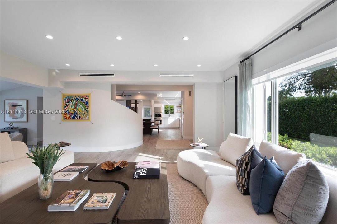 Open-concept interior featuring recessed lighting, curved architectural wall detail, wood-finish flooring, and expansive picture window