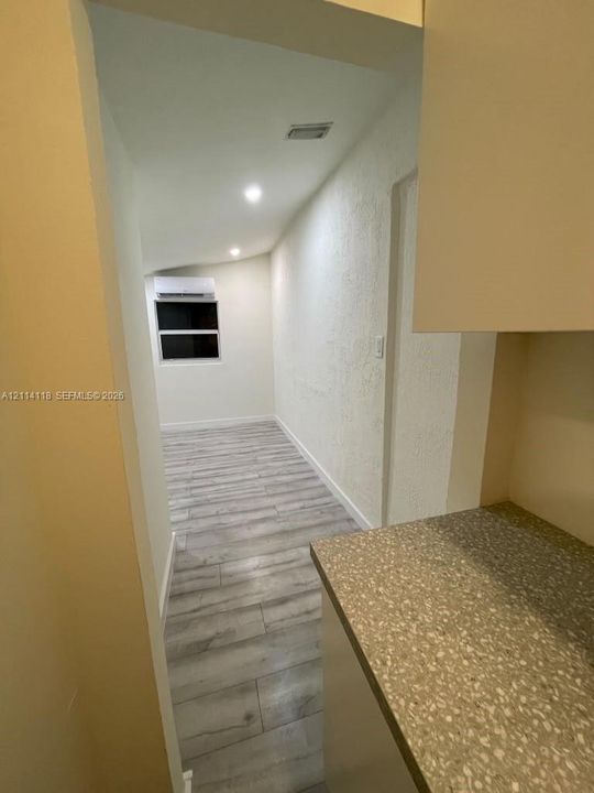 Wood-finish flooring, textured wall surfaces, recessed lighting, and wall-mounted ductless climate control unit