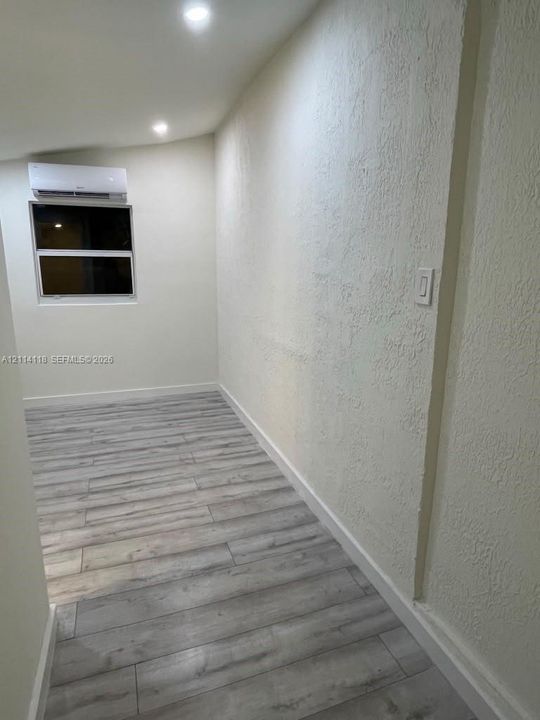 Room interior featuring wood-finish flooring, recessed lighting, and a wall-mounted ductless air conditioning unit
