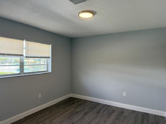 Neutral-toned walls featuring wood-finish flooring, a flush-mount circular light fixture, and horizontal window blinds