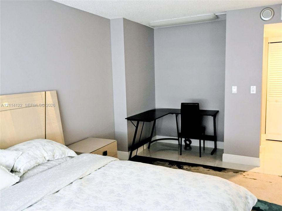 Neutral-toned interior space featuring light grey walls, recessed ceiling lighting, and a white louvered closet door