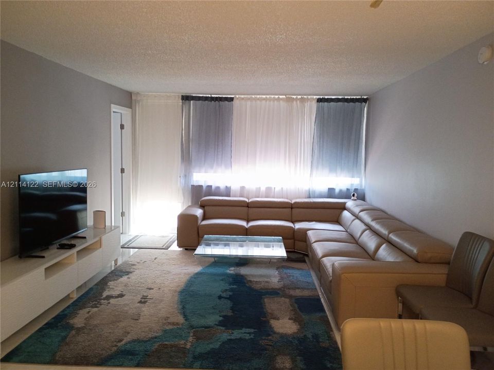 Living area featuring neutral-toned walls, ceiling-height window treatments, and hard-surface flooring