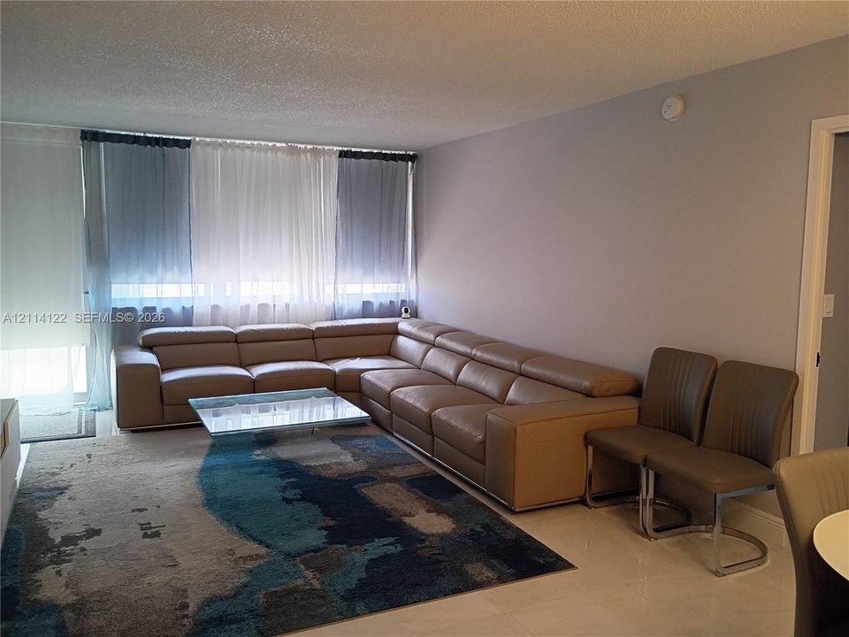 Open-concept living area featuring floor-to-ceiling windows and neutral-tone tile flooring