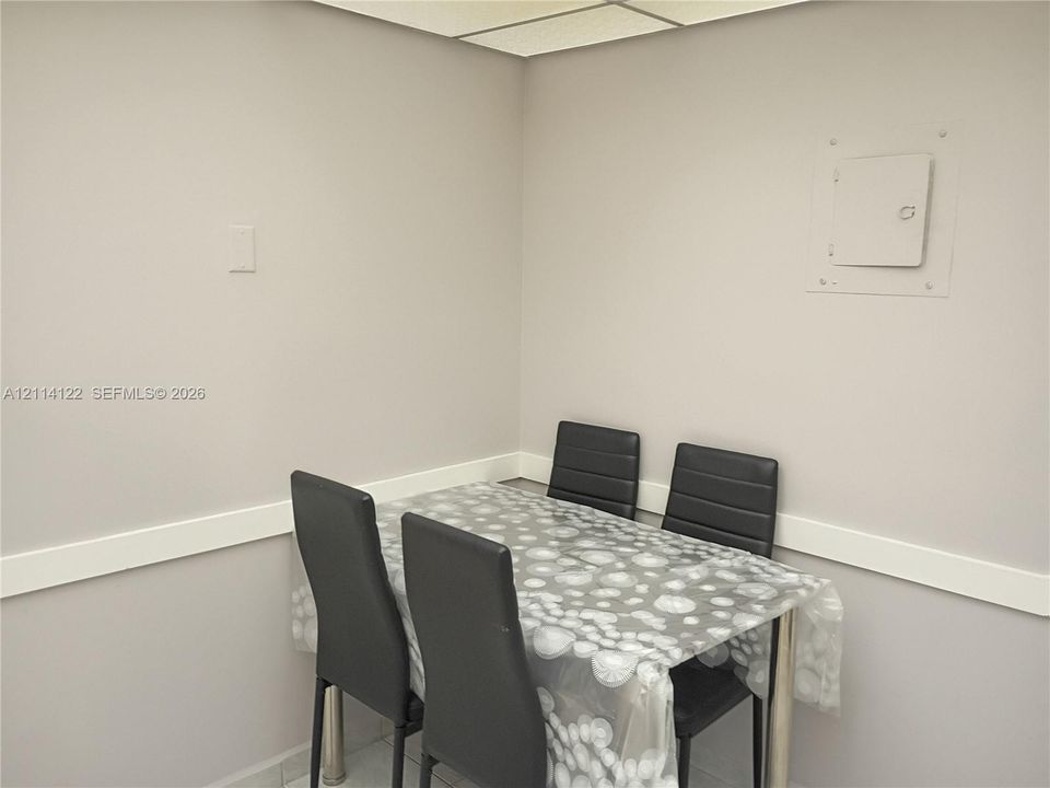 Neutral-toned interior space featuring light-colored wall finish, linear wall molding, and recessed ceiling grid panel