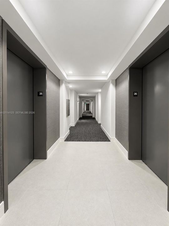 Hallway featuring large-format tile flooring, textured charcoal wall coverings, matte charcoal door frames, and recessed ceiling lighting