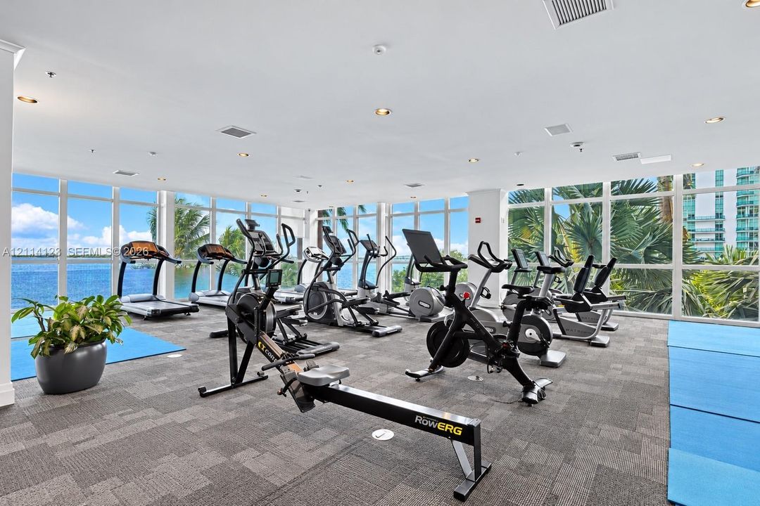 Fitness center featuring floor-to-ceiling windows, panoramic water exposure, recessed lighting, and carpeting