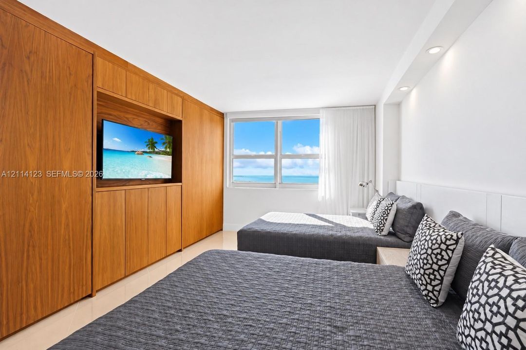 Custom wood-veneer cabinetry with integrated media shelving, large windows with water scenery, and recessed lighting