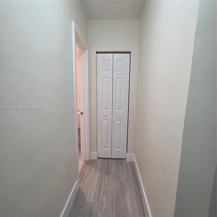 Hallway featuring neutral wall paint, wood-finish flooring, and a white bifold closet door