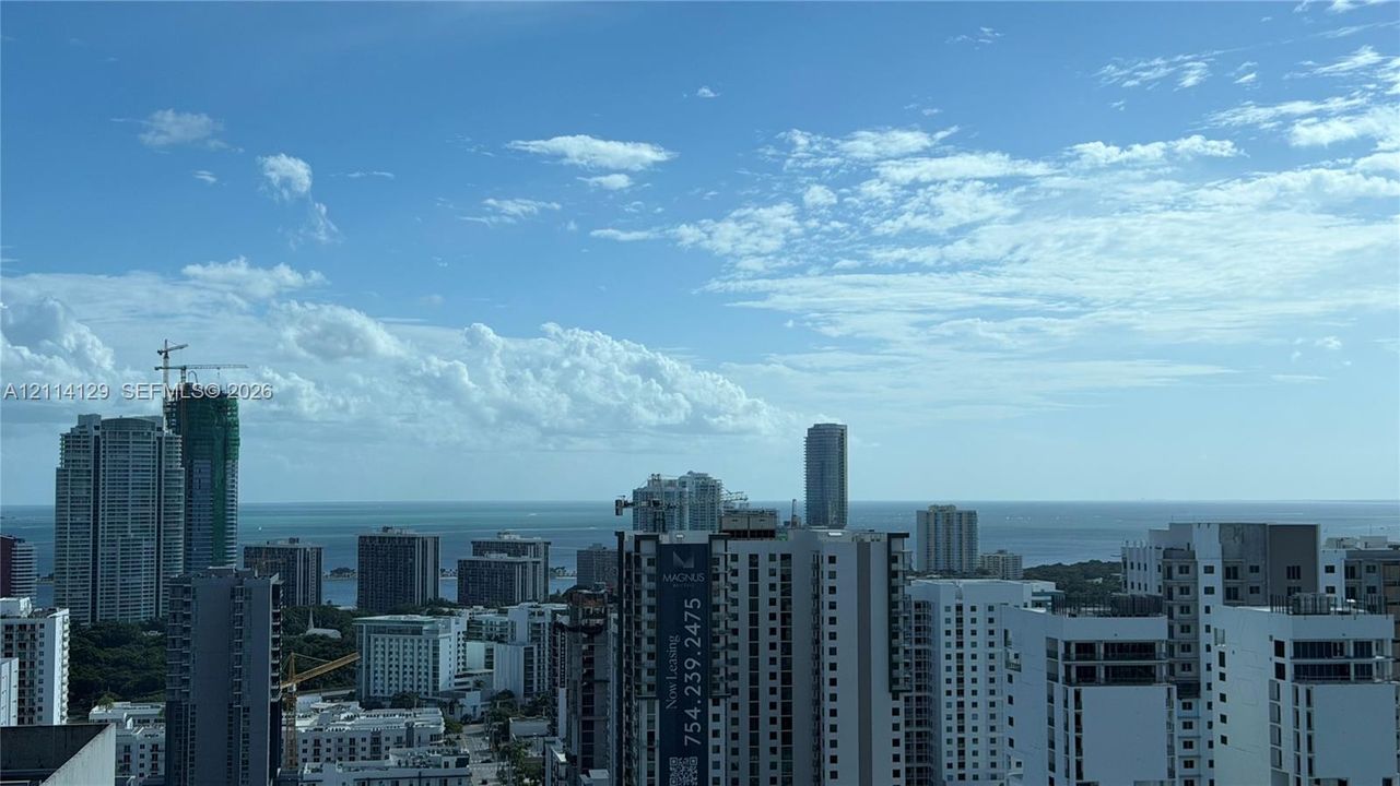 Elevated cityscape featuring dense urban architecture and a vast ocean horizon